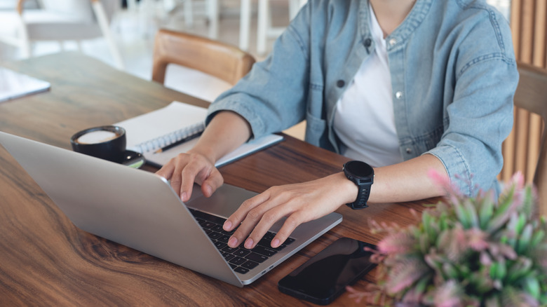 Woman in white shirt and denim jackets researching flooring options online using laptop