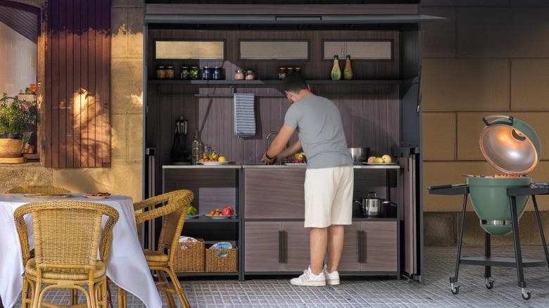 man cleaning outdoor kitchen setup after grilling